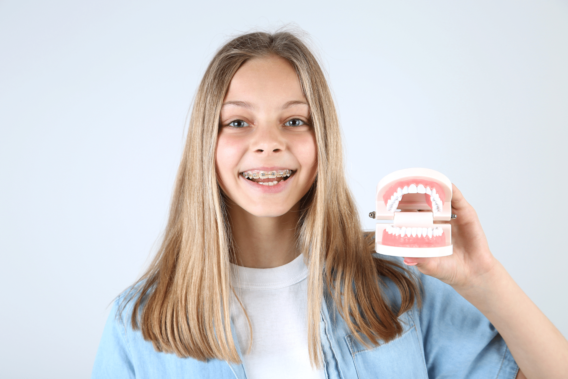 Child with braces holding a dental model during Phase 2 orthodontic treatment in Houston TX